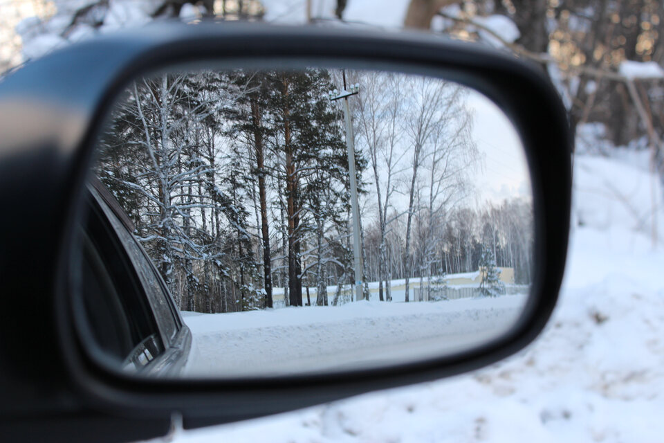 car mirror reflecting a winter snow background